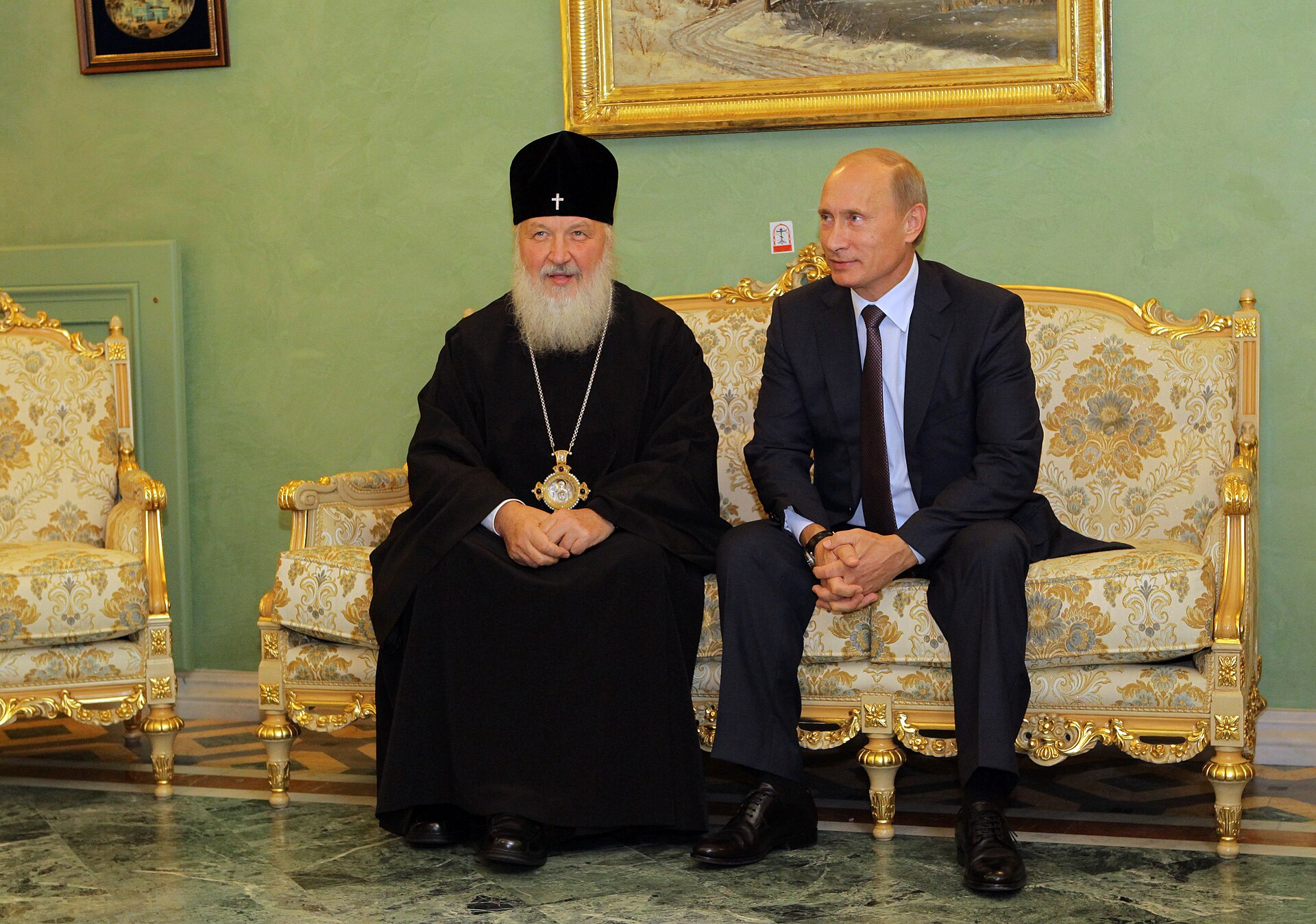 Vladimir Putin and Patriarch Kirill seated together on an ornate gold-trimmed sofa